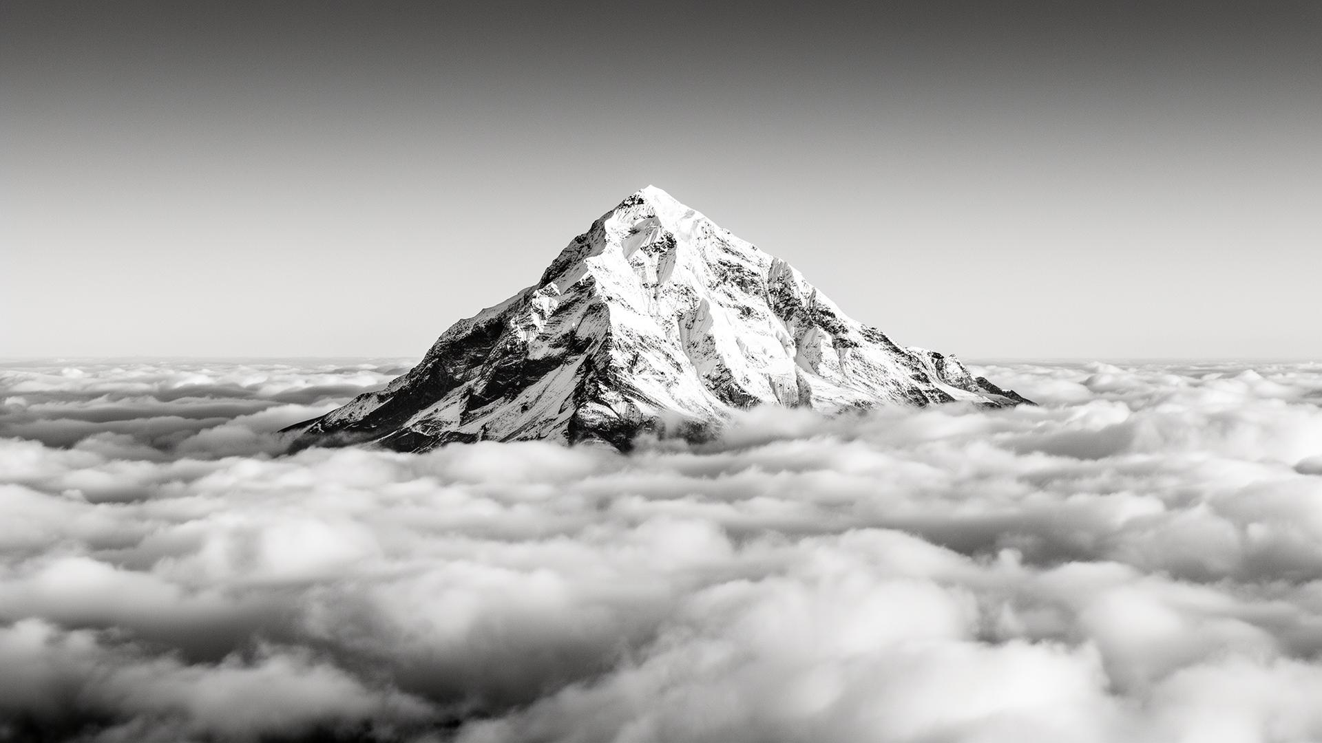 Snow-capped mountain peak rising above a sea of clouds